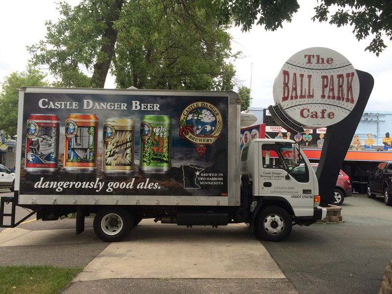 Small delivery truck with beer cans on the outside.